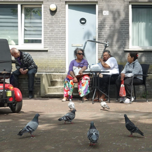 Ouderen in de wijk op een bankje voor hun huis