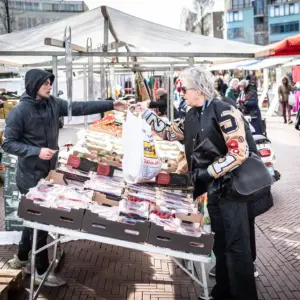 Een vrouw koopt iets bij een marktkraam.