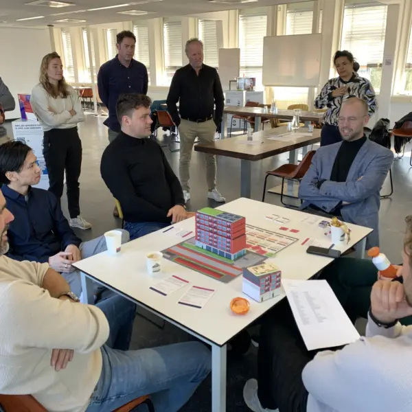 Spelers van de serious game ‘Afwegen van belangen bij optoppen’ zitten rond de tafel en spelen het spel.