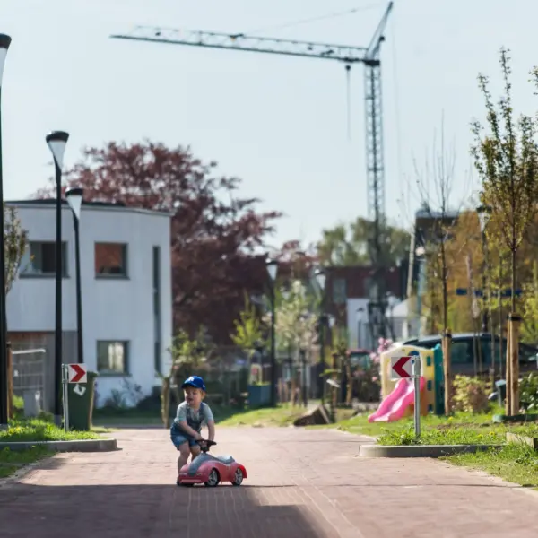 Baby in een straat met een hijskraan op de achtergrond
