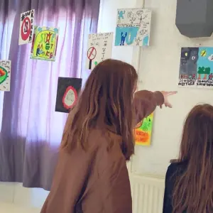 Twee kinderen kijken naar tekeningen van klasgenoten over roken en rookvrij.