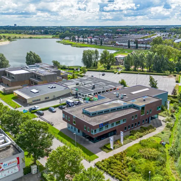 Overzichtsfoto waarop te zien is: bedrijventerrein, woonwijk, een grote waterplas en een weg.