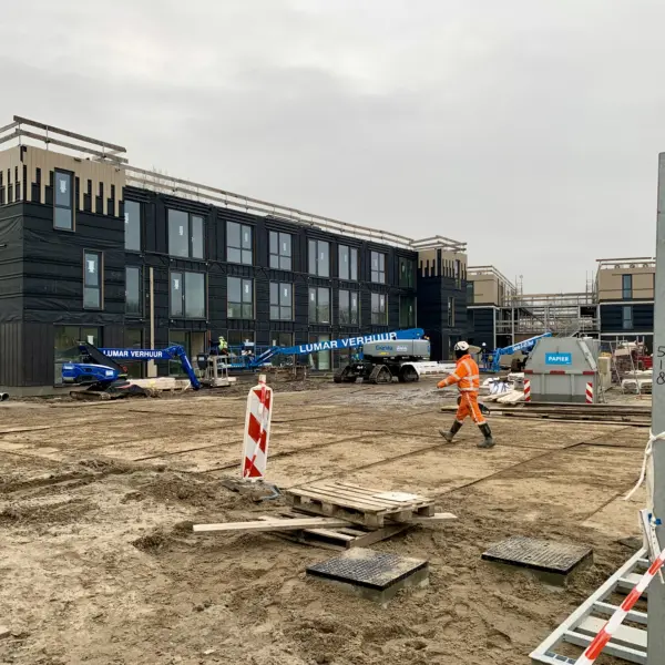 Heemskerk, bouwplaats met bouwvakker en hijskraan en woningen in bouw op de achtergrond