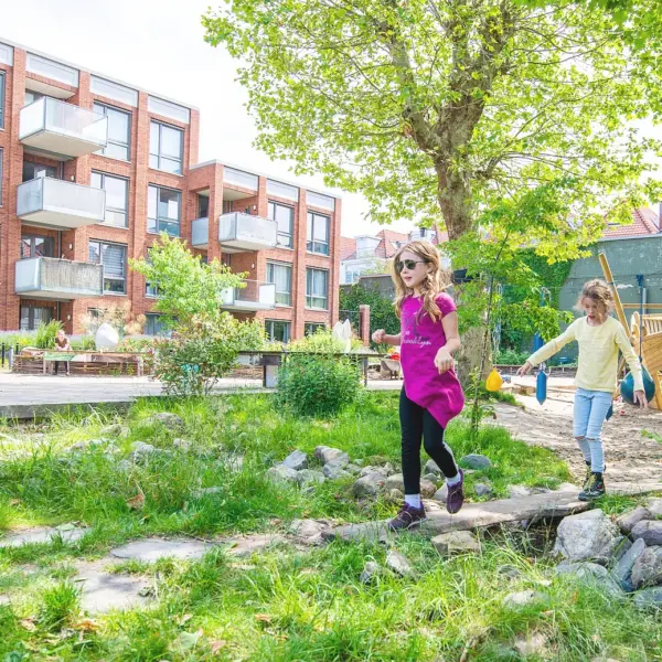Kinderen in een groen parkje met appartementen op de achtergrond