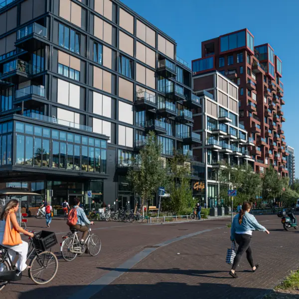 Gestapelde woningbouw met commerciële ruimten op de begane grond in een levendige stedelijke wijk.