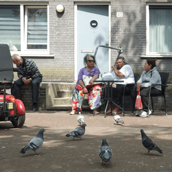 Ouderen in de wijk op een bankje voor hun huis