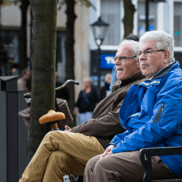 Oudere mannen op een bankje buiten in de stad (foto Ineke Linssen)