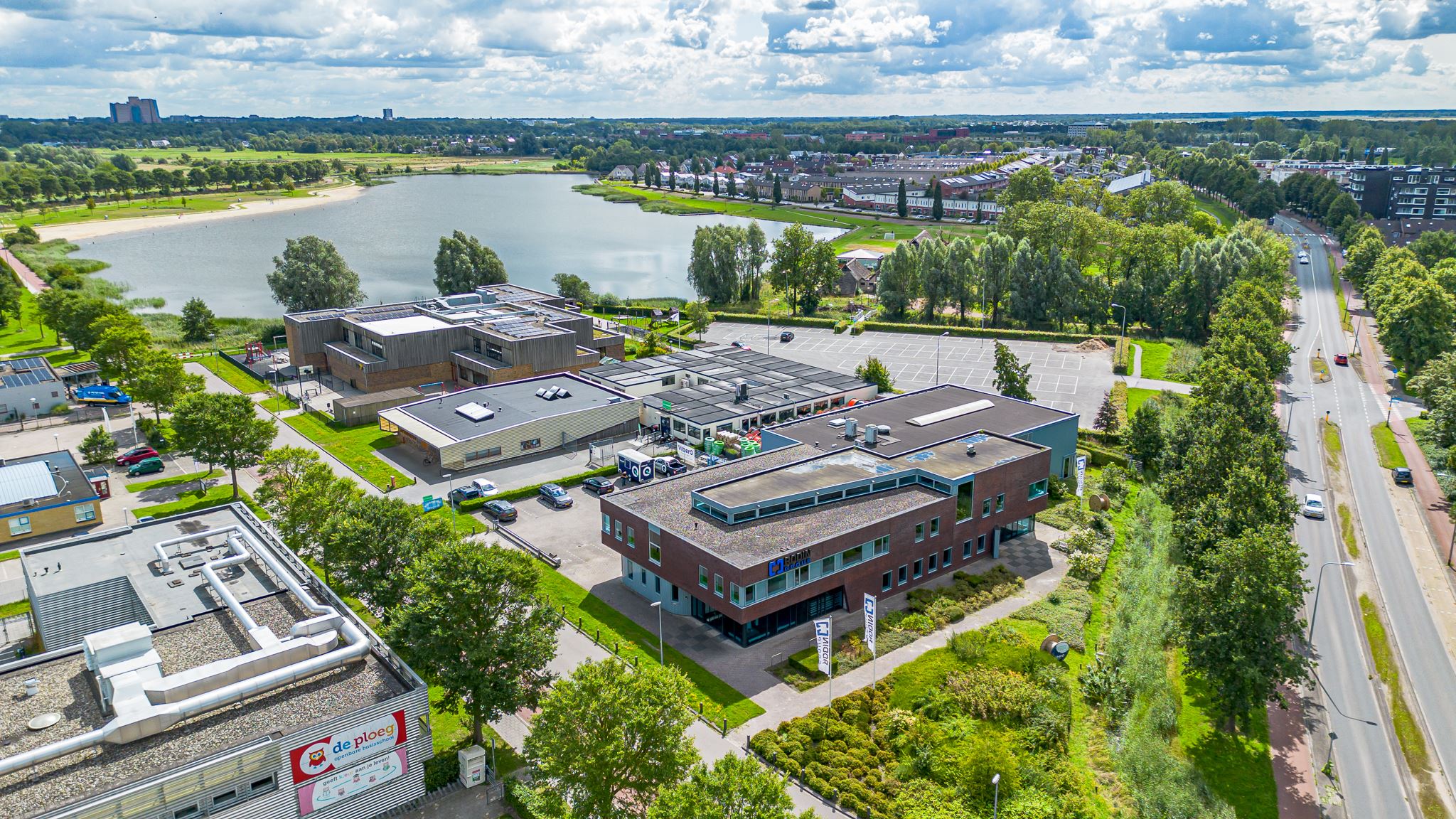 Overzichtsfoto waarop te zien is: bedrijventerrein, woonwijk, een grote waterplas en een weg.