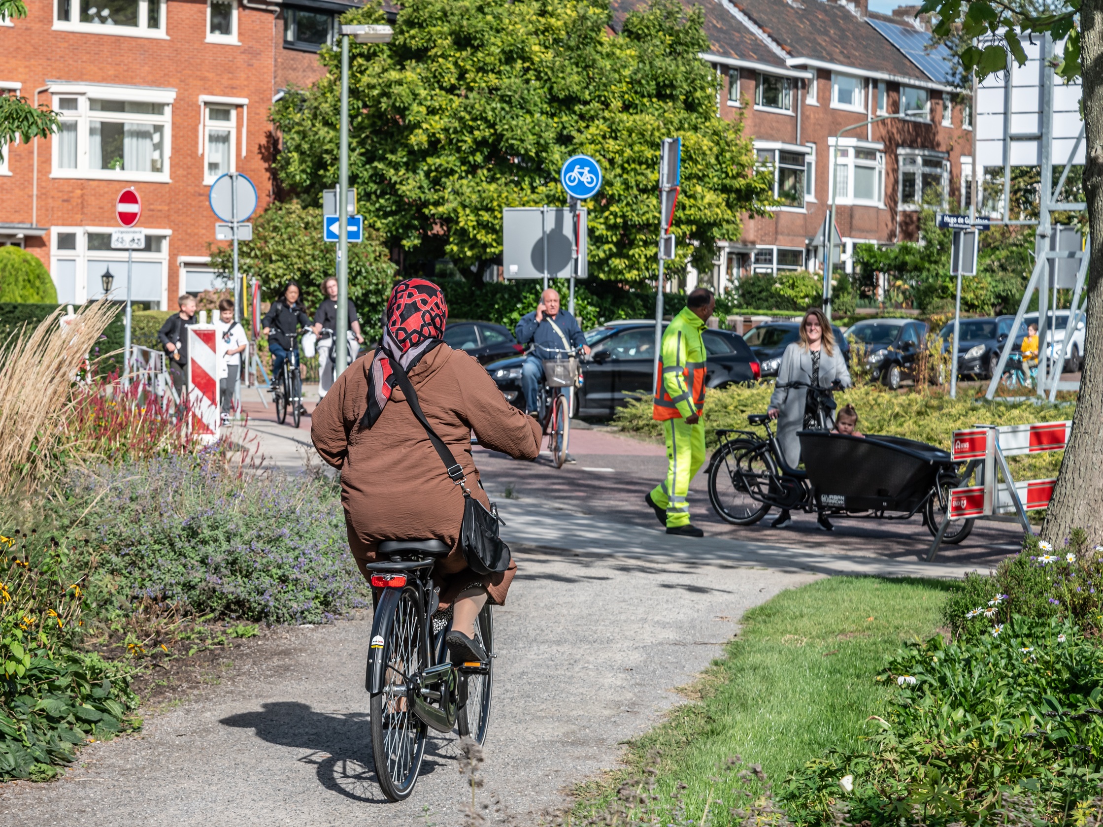 Gevarieerd straatbeeld met verschillende bewoners. Op de achtergrond huizen.